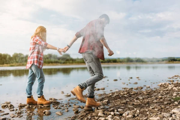 Casal andando ao longo da margem do rio — Fotografia de Stock