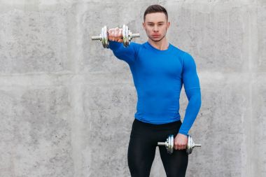 Kaslı vücut geliştirmeci adam dumbbells ile