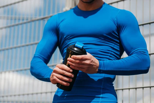 Jovem desportista segurando uma garrafa de água — Fotografia de Stock