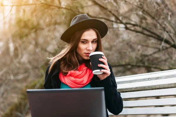 Женщина с кофе и ноутбуком в парке — стоковое фото