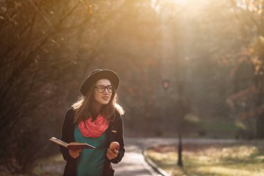 Kız güneşli sonbahar parkta yürüyüş