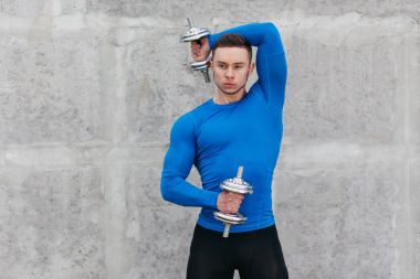 Kaslı vücut geliştirmeci adam dumbbells ile