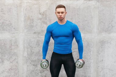 Kaslı vücut geliştirmeci adam dumbbells ile