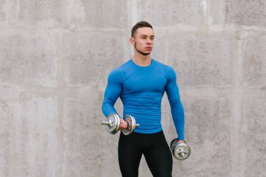 Kaslı vücut geliştirmeci adam dumbbells ile