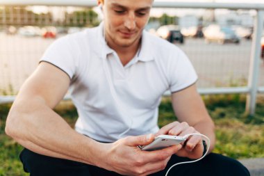 Park yerinde akıllı telefon kullanan adam