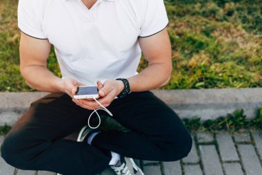 Park yerinde akıllı telefon kullanan adam