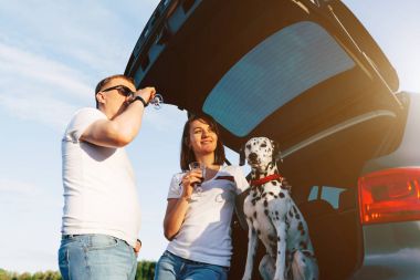 Çift ve araba bagajında oturan köpek