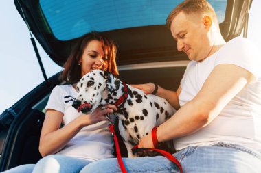 Çift ve araba bagajında oturan köpek