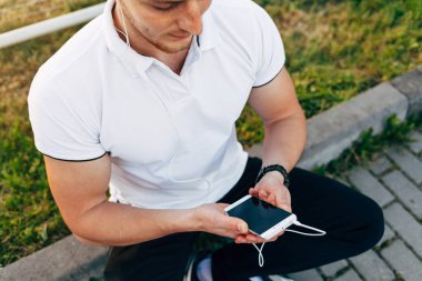 Park yerinde akıllı telefon kullanan adam