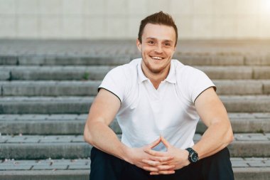 Merdivenlerde oturan kaslı adam