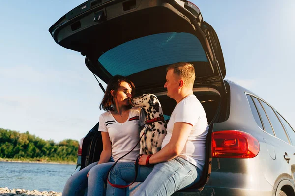 Coppia e cane seduti nel bagagliaio dell'auto — Foto Stock