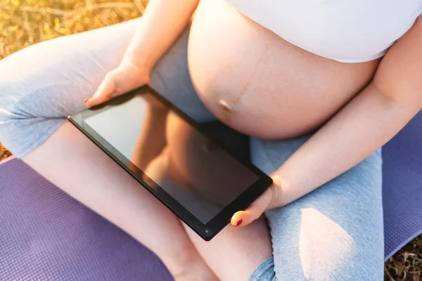 Pregnant woman with tablet outdoors