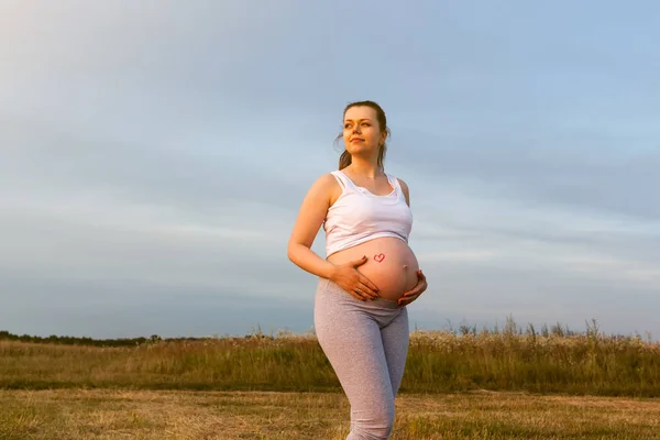 Mujer embarazada en el campo de atardecer Imágenes De Stock Sin Royalties Gratis