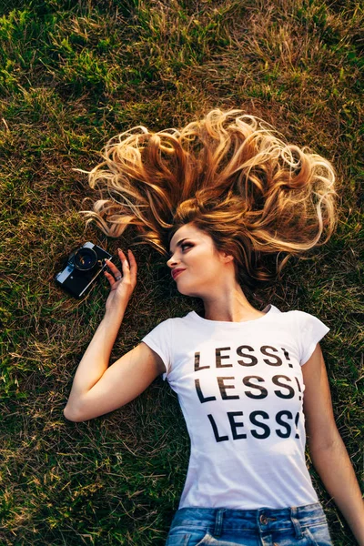 Жінка лежить на газоні з камерою — стокове фото