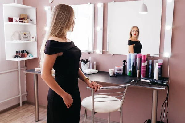 メイクアップ美容サロンに立っていると黒のドレスで美しい女性 — ストック写真