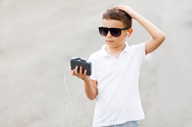 Vintage müzik çalar elinde olan küçük çocuk güneş gözlüğü ve Beyaz tişört closeup portresi