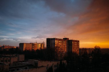Şehrin üzerinde şaşırtıcı günbatımı. Gökyüzü mavi ve turuncu. Evlerin windows yansıması. Pencereden görüntüleme