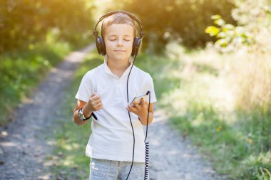 Büyük kulaklıklar giyen ve komik surat ve dans müzik küçük çocuk