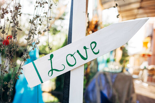 White wooden arrow with word love. Wedding concept on blurred background