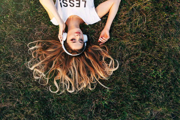 Mujer acostada en la hierba en los auriculares — Foto de Stock