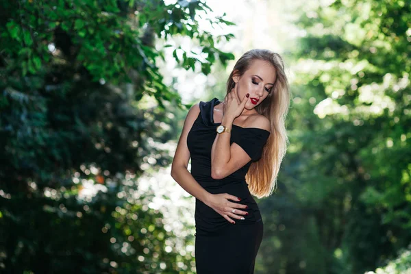 Vrouw in zwarte jurk poseren in park — Stockfoto