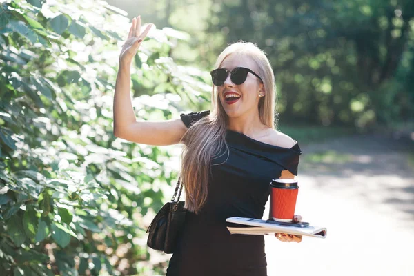 Donna con riviste e caffè nel parco — Foto Stock