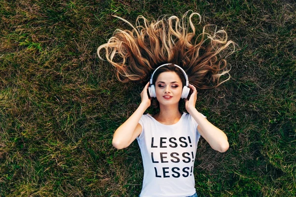 ヘッドフォンで草の上に横たわる女 — ストック写真