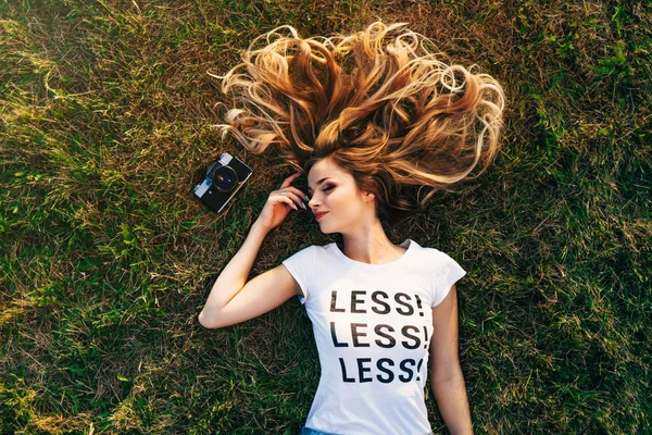 Woman lying on lawn with camera — Stock Photo, Image