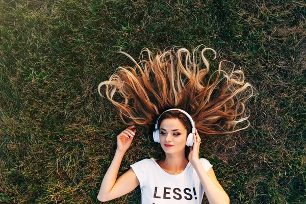 Жінка лежить на траві в навушниках — стокове фото