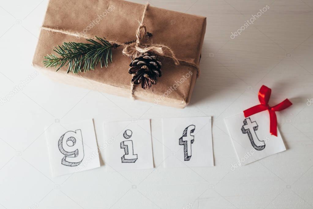 Composition with wrapped gift box and text gift made of letters printed on paper