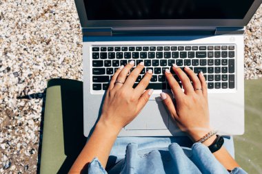 Laptop ile denize sıfır plaj üzerinde oturan genç güzel kadın