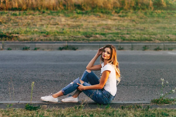 Mulher sentada no lado da estrada — Fotografia de Stock