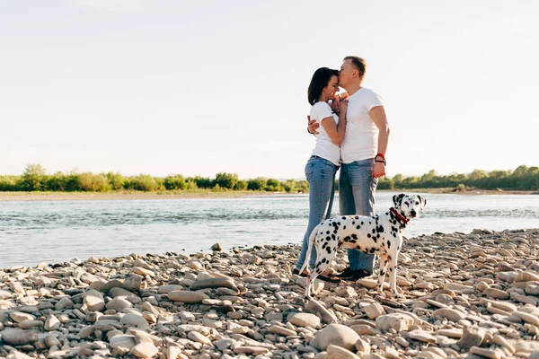 Mutlu genç yetişkin çift ile köpek roadtrip tarihinde portresi. Ekose üzerinde kadınla oturan adam. Açık piknik kavramı. — Stok fotoğraf