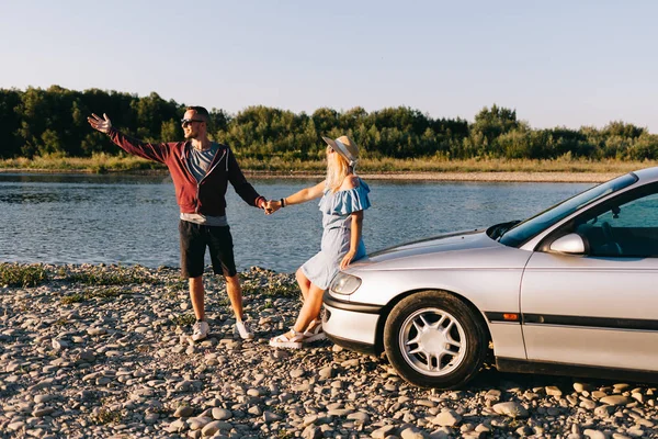 Feliz casal viajante de pé perto do carro aberto tronco e assistir o nascer do sol — Fotografia de Stock