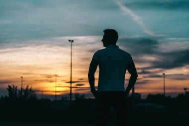 Gün batımı arka planda genç bir adam silüeti