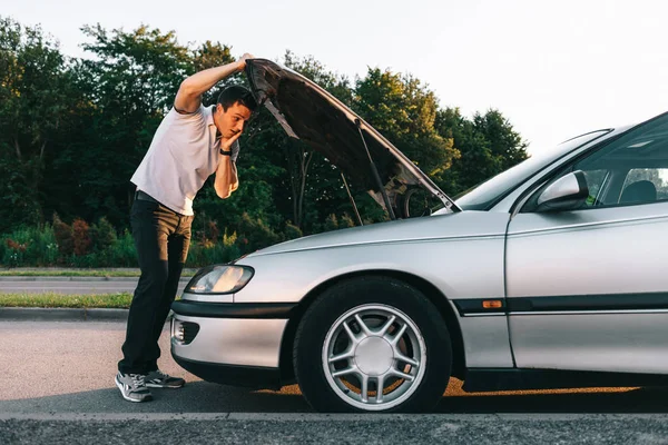 Ελκυστική Καυκάσιος νεαρός σε λευκό t-shirt στέκεται από το σπασμένο αυτοκίνητο — Φωτογραφία Αρχείου