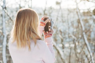 Genç beyaz çekici sarışın kız pembe kazak ve örme eşarp kış Park retro film kamera açık tutar