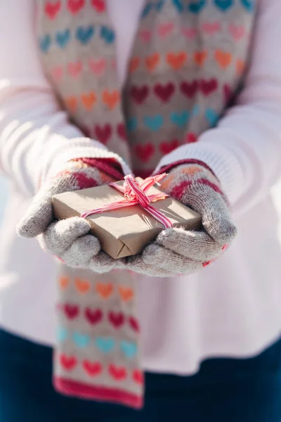Young girl holds gift in hands in winter park