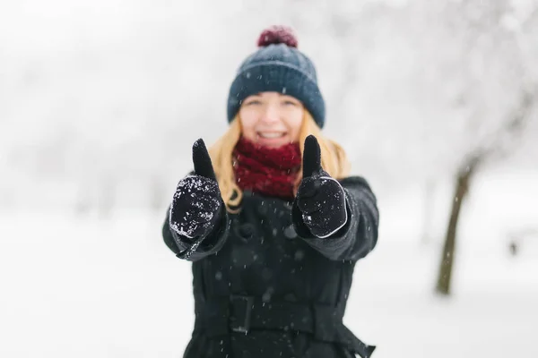 Joven chica rubia caucásica en abrigo negro y bufanda de punto rojo camina en el parque de invierno —  Fotos de Stock