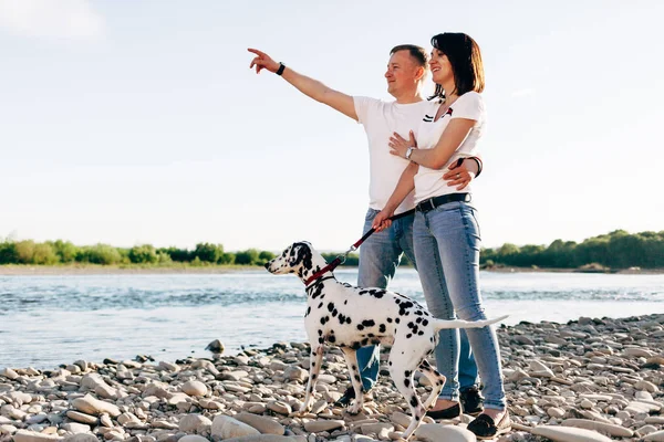 Ritratto di giovane coppia adulta felice con cane in viaggio. Uomo seduto su un plaid con una donna. concetto di picnic all'aperto . — Foto Stock