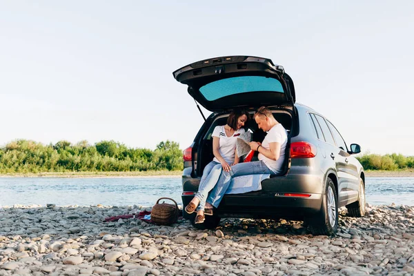 Glada paret sitter i bilen öppna bål och titta på kartan, roadtrip koncept — Stockfoto