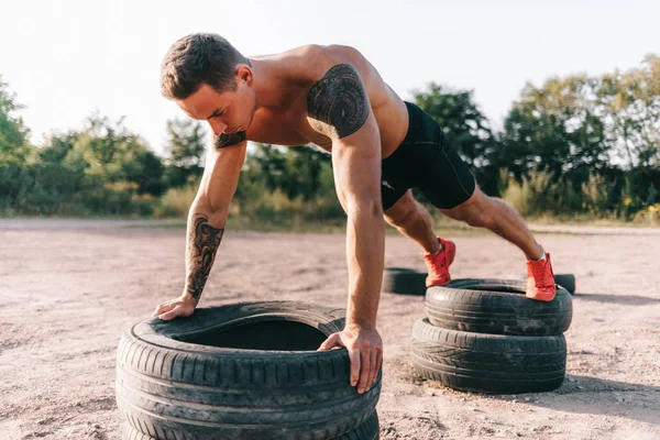 Jonge Kaukasische atleet in tatoeages, opleiding outdoor en poseren — Stockfoto