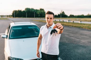 Genç çekici beyaz adam arabanın yanında beyaz t-shirt ayakta