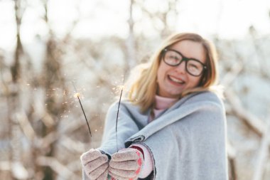 Genç beyaz çekici sarışın kız pembe kazak ve örme eşarp kış park bengal ışıklar açık tutar