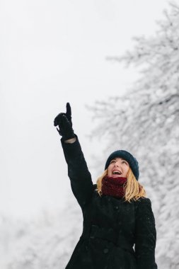 Siyah palto ve kırmızı örme eşarp genç Beyaz sarışın kız kış parkta yürüyor