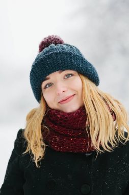 Siyah palto ve kırmızı örme eşarp genç Beyaz sarışın kız kış parkta yürüyor