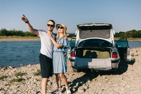 Happy cestovatel pár stojící poblíž auto otevřít kufr a sledovat východ slunce — Stock fotografie