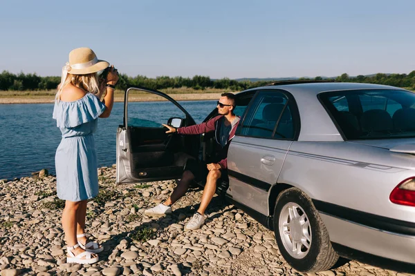 Feliz viajero pareja de pie cerca de coche abierto tronco y ver el amanecer —  Fotos de Stock