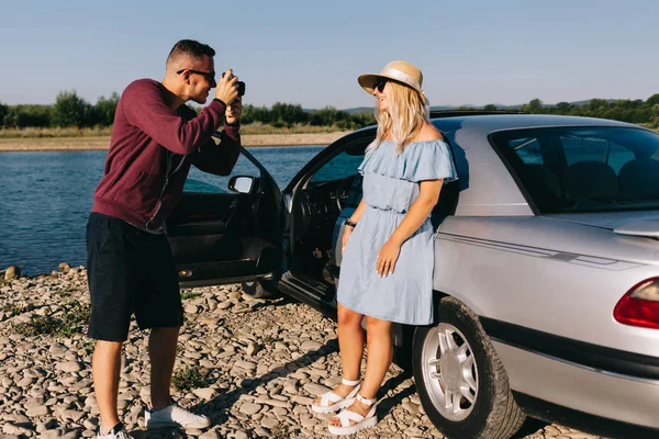 Feliz casal viajante de pé perto do carro aberto tronco e assistir o nascer do sol — Fotografia de Stock