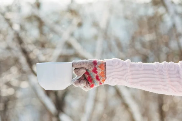 Молодая девушка держит чашку чая в руке в зимнем парке — стоковое фото